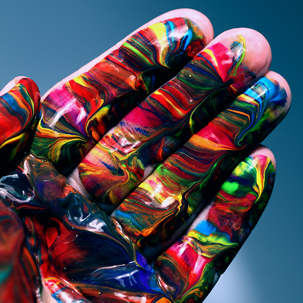 Photo of a hand covered in multi-coloured paint