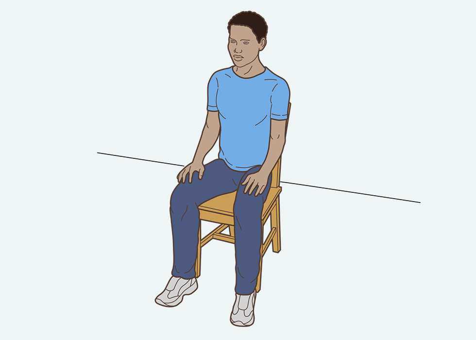 Person sitting in a chair with hands resting on their thighs.