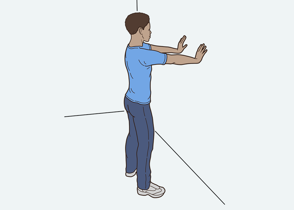Person standing up with their hands flat on a wall.