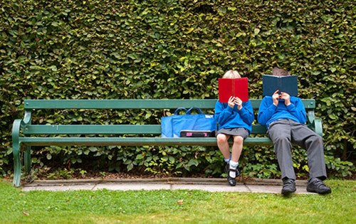 2 students reading on park bench